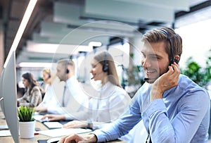 Portrait of call center worker accompanied by his team. Smiling customer support operator at work