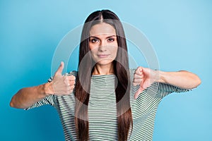 Portrait of calm attractive lady show two hands thumb up down wear white green isolated on blue color background