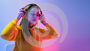 Portrait of a calm Caucasian woman wearing a yellow hoodie sitting and wearing wireless headphones, and posing isolated.