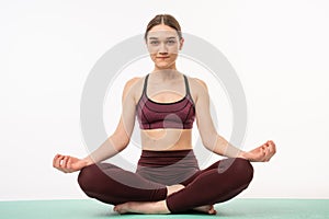 Portrait of a calm european fitness woman resting while sitting and meditating isolated over white background