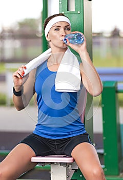 Portrait of calm female sportswoman having water break during her training outdoors