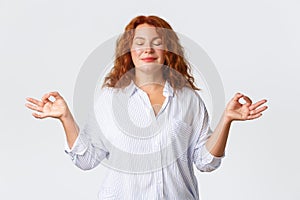 Portrait of calm and peaceful, smiling middle-aged woman with red hair, looking patient and relaxed, close eyes and