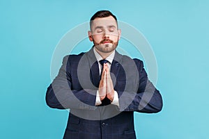 Portrait of calm relaxed young man with beard wearing official style suit standing with raised arms