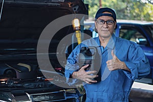 Portrait of car mechanic with engine oil pack at garage and car maintenance station