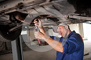 Portrait of car mechanic working with tools under car