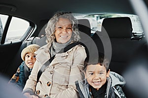 Portrait, car ride and grandmother relax with children or grandchildren while travel or on a road trip in the backseat