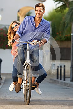 Portrait of carefree couple riding bicycle together on path