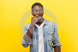 Portrait of carefree funny man picking nose and sticking out tongue. indoor studio shot isolated on yellow background