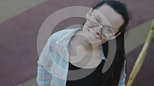 Portrait of carefree young woman smiling and looking at camera with urban background. Cheerful ucasian cagirl wearing