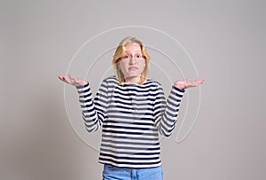 Portrait of careless female entrepreneur spreading hands and shrugging shoulders on white background