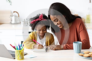 Portrait Of Caring Black Mom Helping Her Little Daughter With Homework