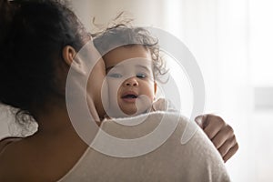 Portrait of caring ethnic mom cuddle little baby daughter