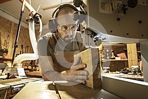 Portrait of a carpenter inside his carpentry workshop using a band saw