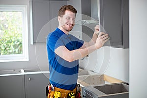 Portrait Of Carpenter Installing Luxury Modern Fitted Kitchen