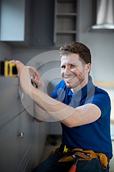 Portrait Of Carpenter Installing Luxury Modern Fitted Kitchen