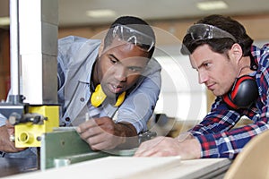 portrait carpenter working with apprentice in joinery workshop