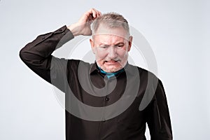 Portrait of casual mature man in black shirt thinking and looking puzzled