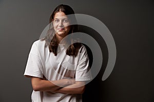 Portrait of casual natural teen girl with restrained smile and folded hands