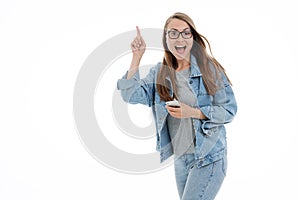 Portrait of a casual smiling young woman dressed in total denim blue jeans holding mobile phone
