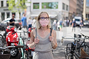 Portrait of casual yound woman walking on the street wearing protective mask as protection against covid-19 virus