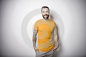 portrait of casual young man with beard and tattoo and Burnt Orange shirt on white background