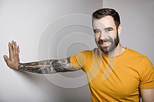 portrait of casual young man with beard and tattoo and Burnt Orange shirt on white background