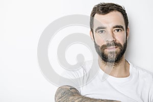 portrait of casual young man with beard and tattoo on white background