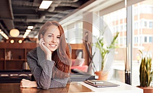 Portrait Of Casually Dressed Young Businesswoman Working At Desk In Modern Open Plan Workplace