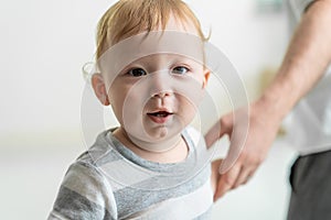 Portrait of Caucasian adorable baby boy kid smile, looking at camera. Cute little young toddler son feel happy while learn to walk