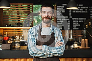 Portrait of caucasian barista guy standing with arms crossed in street cafe or coffeehouse outdoor