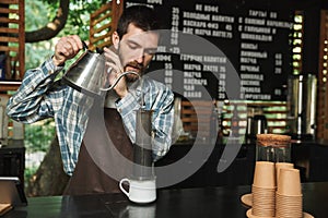Portrait of caucasian barista man making coffee while working in street cafe or coffeehouse outdoor