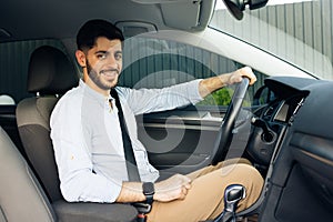 Portrait of caucasian bearded businessman driving car. cheerful man in his car looking camera.