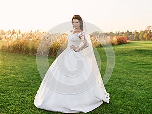 Portrait of caucasian beautiful attractive woman bride in traditional european white dress standing on the field
