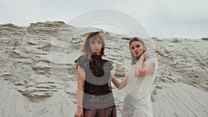 Portrait of caucasian beautiful young females in white and black dresses back to back and smiling to camera or looking