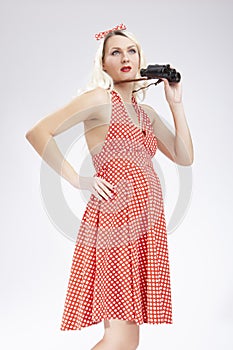 Portrait of Caucasian Blond Girl Posing in Pin-up Style With Binoculars in Front of Her Face. Against White