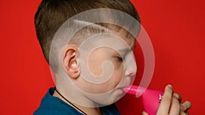 Portrait of a caucasian boy 7 years old inflating a balloon. The child learns to inflate balloons with his lips. Family kids holid