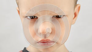 Portrait caucasian boy 4 years old, angry child expresses emotions of discontent or anger looks at camera on white