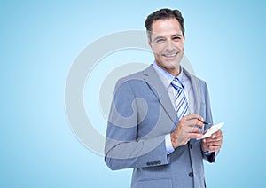 Portrait of caucasian businessman smiling an taking notes against copy space on blue background