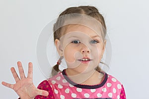 Portrait of caucasian child of three years old shows five fingers to show number five looking at camera on the white background