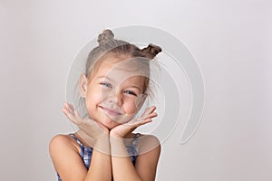 Portrait of caucasian cute little girl of five years old holdings head chin on hands on the white background looking at