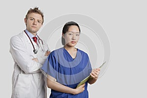 Portrait of a Caucasian doctor standing with an Asian nurse over gray background