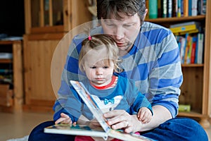 Portrait of caucasian father hold story book reading with daughter little girl. Home school learn from teacher