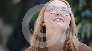 Portrait caucasian girl blonde successful lucky woman in glasses looks at screen of mobile phone wins online message