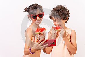 Portrait of a Caucasian girl and boy eating watermelon and taking selfie -summer vacation concept
