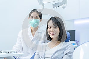 Portrait of Caucasian girl patient smile, sitting on dental chair after doctor and assistant provide medical service. Young woman