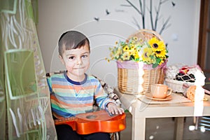 Portrait of caucasian little charming boy with a toy guitar in selective focus