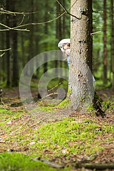 Portrait of Caucasian Little Girl Lurking Around the Tree