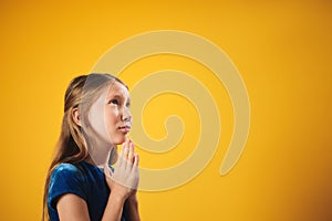 Portrait Of Caucasian Little Girl Praying God On Yellow Background