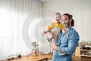 Portrait of Caucasian loving father hold baby boy child in living room. Happy family, attractive caring young dadd carry his