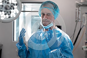 Portrait of caucasian male doctor standing in operating theatre wearing face mask